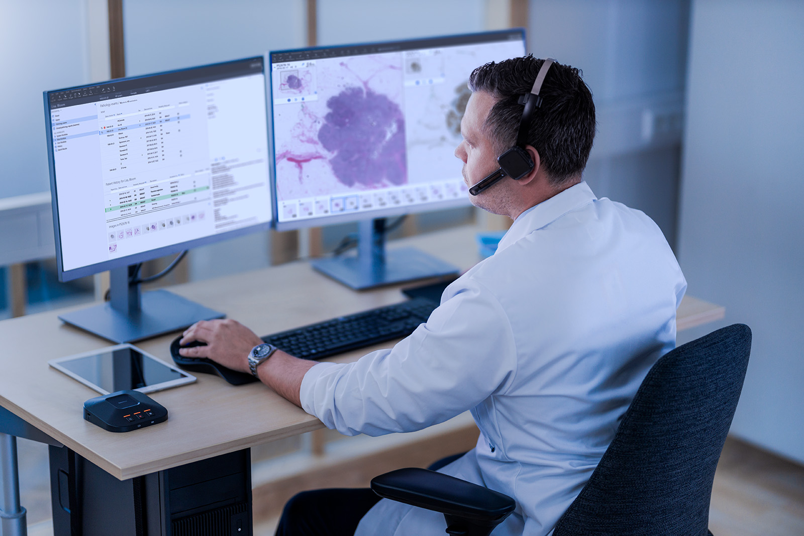 Male pathologist sitting in front of a monitor studiying a case with headset